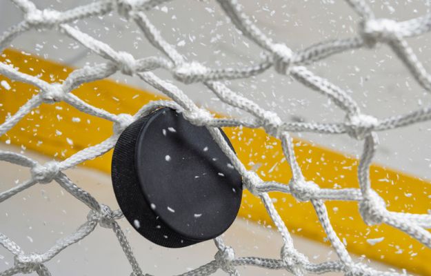 Close-up of a hockey puck hitting the net.