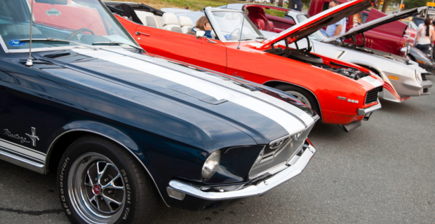 A row of classic muscle cars lined up at a collector car show in Canada.